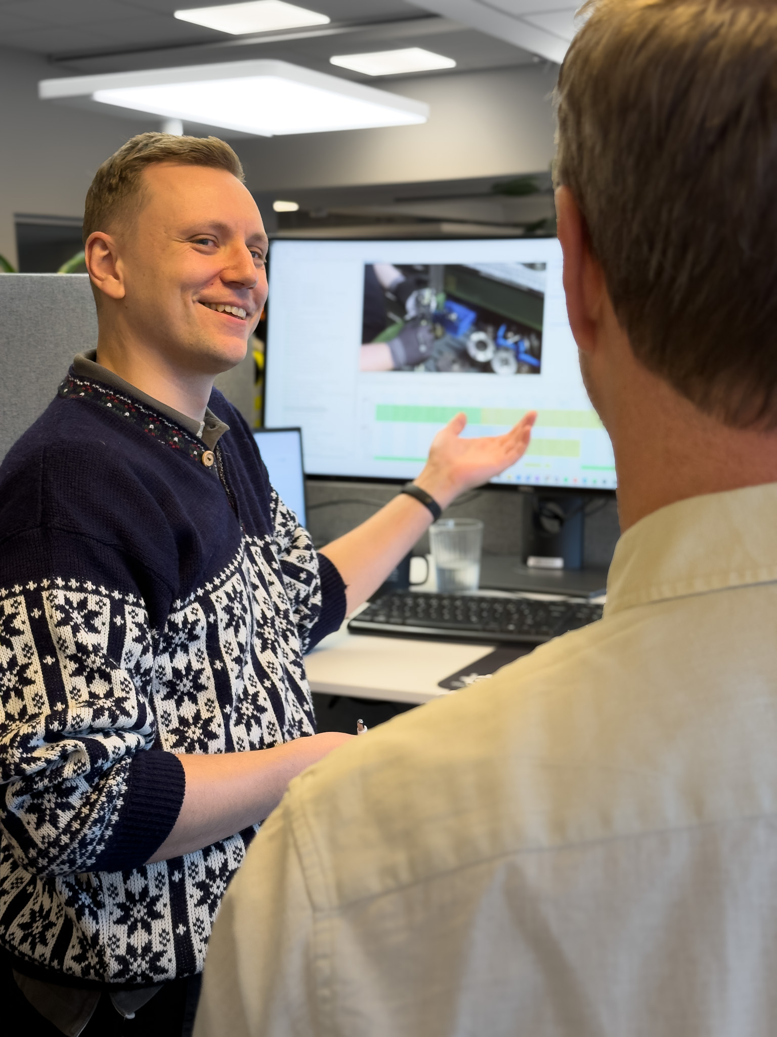 Två kollegor diskuterar en tidstudie framför en skärm för att uppnå effektiv produktion med ny teknik och digitala verktyg